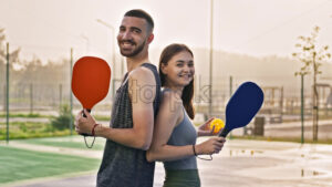 VIDEO Man and woman standing back to back with pallets in their hands after playing pickleball after rain - Starpik