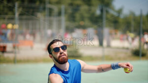VIDEO Man in blue shirt playing tennis on a blue and green court on a sunny day - Starpik