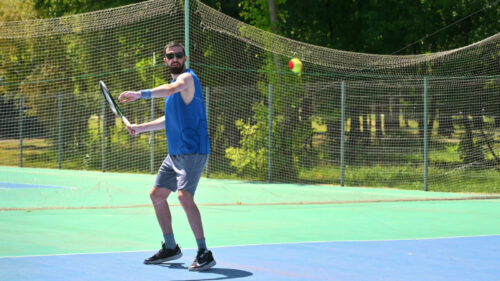 VIDEO Man in blue shirt playing tennis on a blue and green court on a sunny day - Starpik