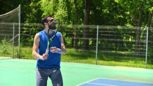 VIDEO Man in blue shirt playing tennis on a blue and green court on a sunny day - Starpik