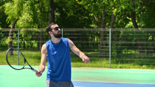 VIDEO Man in blue shirt playing tennis on a blue and green court on a sunny day - Starpik