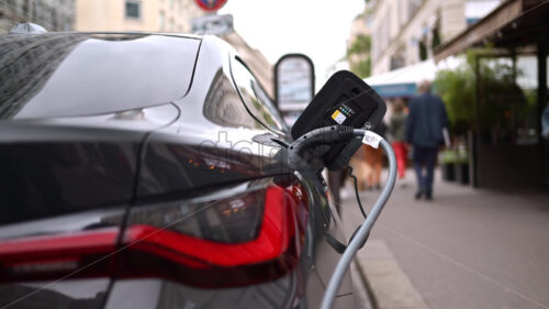 VIDEO Paris, France – June 18, 2024: Back view of a black BMW i4 car charging on the street - Starpik