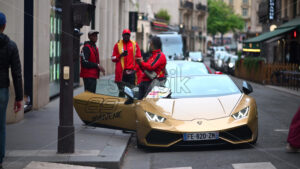 VIDEO Paris, France – June 18, 2024: Three men in red jackets standing near a golden Lamborghini Huracan - Starpik