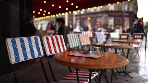 VIDEO Tables at a cafe with blurred people walking in the rain on the background - Starpik