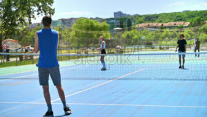 VIDEO Two men and a woman playing tennis on a blue and green court on a sunny day - Starpik