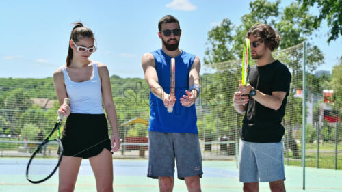 VIDEO Two men and a woman practicing tennis on a blue and green court on a sunny day - Starpik