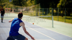 VIDEO Two men playing tennis on a blue and green court on a sunny day - Starpik