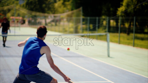 VIDEO Two men playing tennis on a blue and green court on a sunny day - Starpik