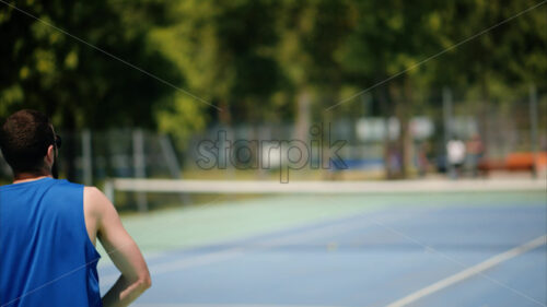 VIDEO Two men playing tennis on a blue and green court on a sunny day - Starpik