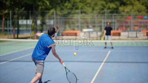 VIDEO Two men playing tennis on a blue and green court on a sunny day - Starpik