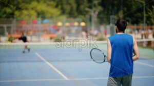 VIDEO Two men playing tennis on a blue and green court on a sunny day - Starpik