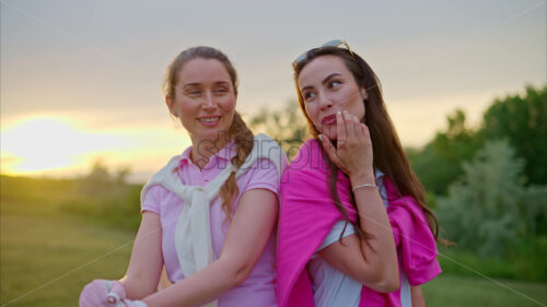 VIDEO Two women dressed in white and pink clothes, holding golf clubs and laughing on the course - Starpik