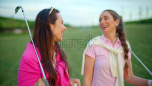 VIDEO Two women dressed in white and pink clothes, holding golf clubs and laughing on the course - Starpik