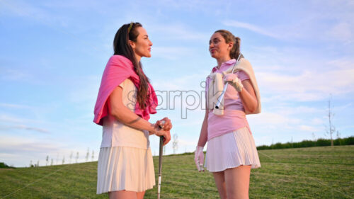 VIDEO Two women dressed in white and pink clothes, holding golf clubs and talking on the course - Starpik