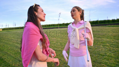 VIDEO Two women dressed in white and pink clothes, holding golf clubs and talking on the course - Starpik