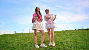 VIDEO Two women dressed in white and pink clothes, holding golf clubs and talking on the course - Starpik