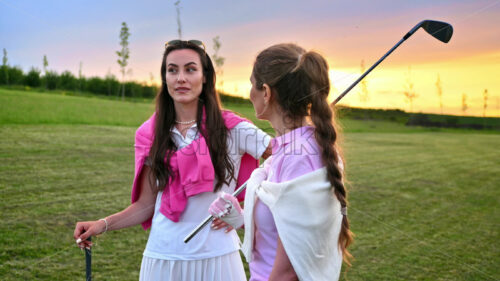 VIDEO Two women dressed in white and pink clothes, holding golf clubs and talking on the course - Starpik