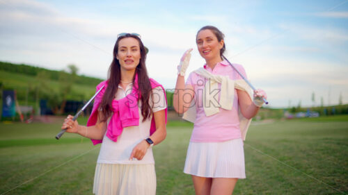 VIDEO Two women dressed in white and pink clothes, holding golf clubs and talking on the course - Starpik