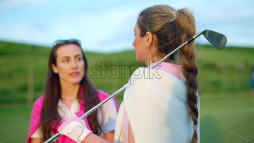 VIDEO Two women dressed in white and pink clothes, holding golf clubs and talking on the course - Starpik