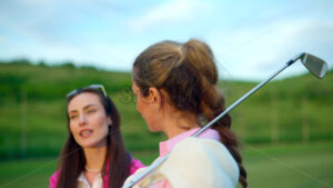 VIDEO Two women dressed in white and pink clothes, holding golf clubs and talking on the course - Starpik