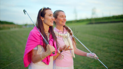 VIDEO Two women dressed in white and pink clothes, holding golf clubs and talking on the course - Starpik