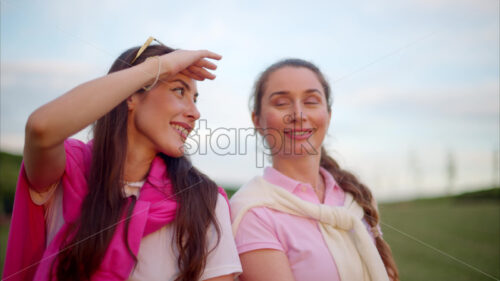 VIDEO Two women dressed in white and pink clothes, holding golf clubs and talking on the course - Starpik