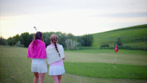 VIDEO Two women dressed in white and pink clothes, with golf clubs on their shoulders, walking and talking on the golf course - Starpik