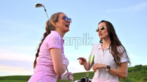 VIDEO Two women holding golf clubs talking on the course on a sunny day - Starpik