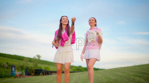 VIDEO Two women in white and pink clothes playing with a white golf ball on the course - Starpik