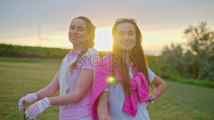 VIDEO Two women in white and pink clothes, posing with golf clubs in their hands, on a grass field - Starpik