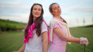 VIDEO Two women in white and pink clothes, posing with golf clubs in their hands, on a grass field - Starpik