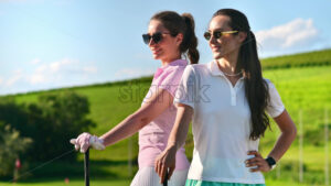 VIDEO Two women standing back to back with golf clubs in their hands, on a grass field - Starpik