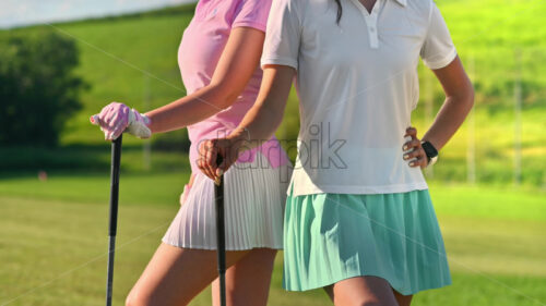 VIDEO Two women standing back to back with golf clubs in their hands, on a grass field - Starpik