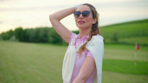 VIDEO Woman dressed in white and pink standing on a field, looking around - Starpik
