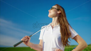 VIDEO Woman dressed in white and pink standing on a field with a golf club on her shoulder - Starpik