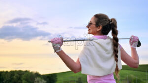VIDEO Woman holding a golf club on her shoulders, watching the sunset - Starpik