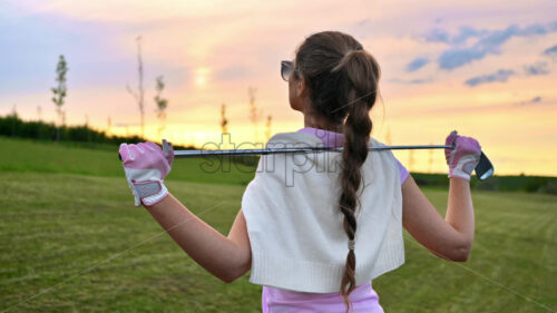 VIDEO Woman holding a golf club on her shoulders, watching the sunset - Starpik