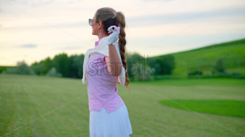 VIDEO Woman holding a golf club on her shoulders, watching the sunset - Starpik