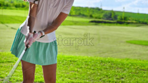 VIDEO Woman in green skirt playing golf on a grass field on a sunny day - Starpik