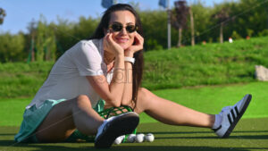 VIDEO Woman in green skirt standing on the golf course near a bucket with balls - Starpik
