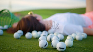VIDEO Woman lying on the golf course near a bucket with spilled balls - Starpik