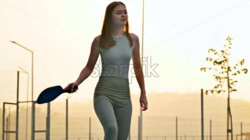 VIDEO Woman playing pickleball on a blue and green court at sunrise, after rain - Starpik