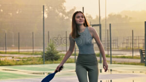 VIDEO Woman playing pickleball on a blue and green court at sunrise, after rain - Starpik