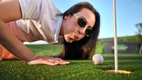 VIDEO Woman trying to push a golf ball into the hole by blowing on it - Starpik