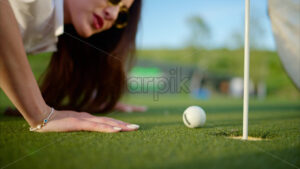 VIDEO Woman trying to push a golf ball into the hole by blowing on it - Starpik