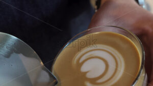 VIDEO Close up of a barista making latte art into a glass of coffee - Starpik