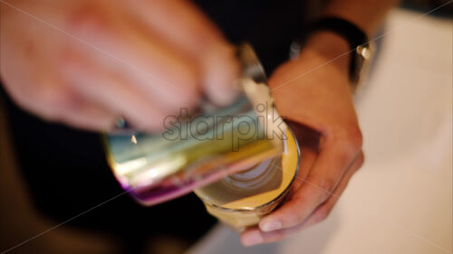 VIDEO Close up of a barista pouring steamed milk into a glass of coffee - Starpik