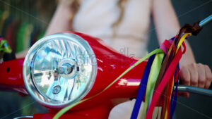 VIDEO Woman standing on a red scooter with colourful decoration hanging from the mirrors - Starpik