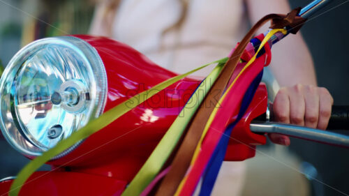 VIDEO Woman standing on a red scooter with colourful decoration hanging from the mirrors - Starpik