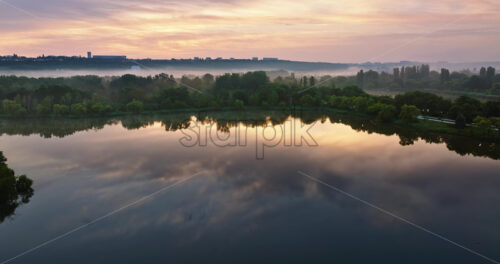 VIDEO Aerial drone view of a lake surrounded by trees in Chisinau, Moldova at sunrise - Starpik